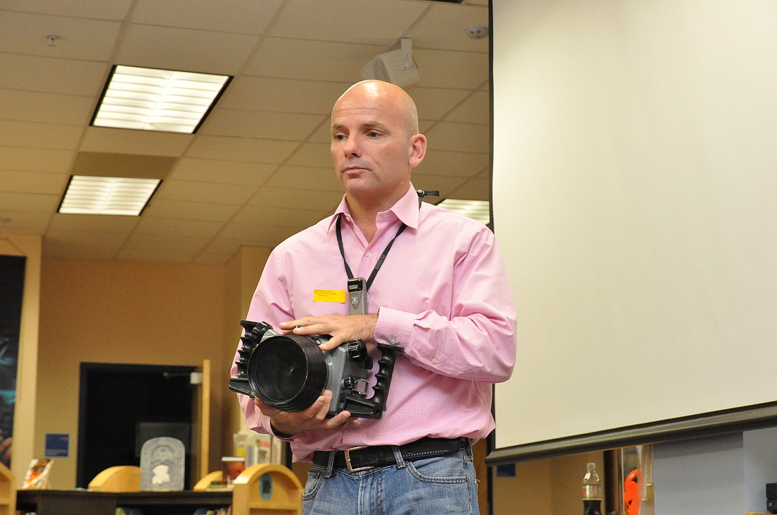 Michael Patrick OÃ¢â‚¬â„¢Neill shows the student assembly the underwater housing for his camera.