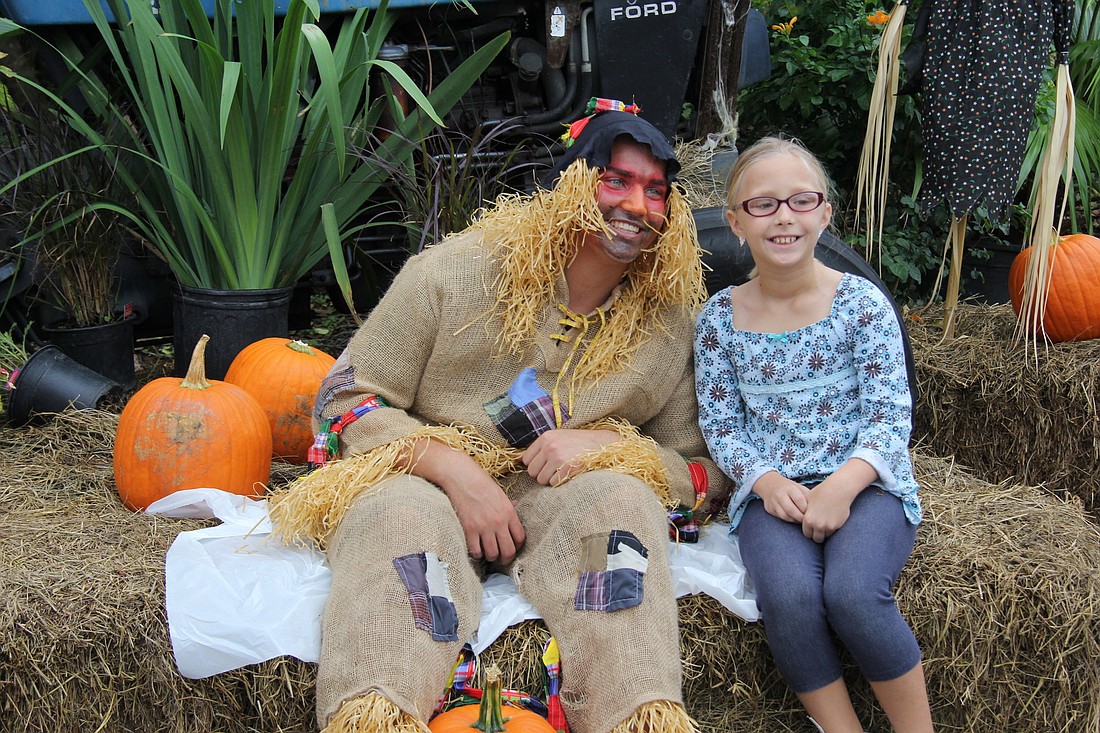 Madelyn Maenner seizes a photo op with a scarecrow.