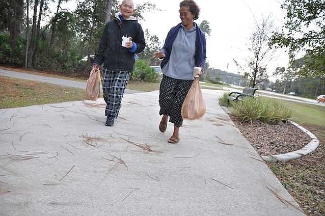 Nay Ouk and Cea Umak walk north on Belle Terre Parkway from the Town Center Shooping Plaza Friday morning. Photo by Shanna Fortier.