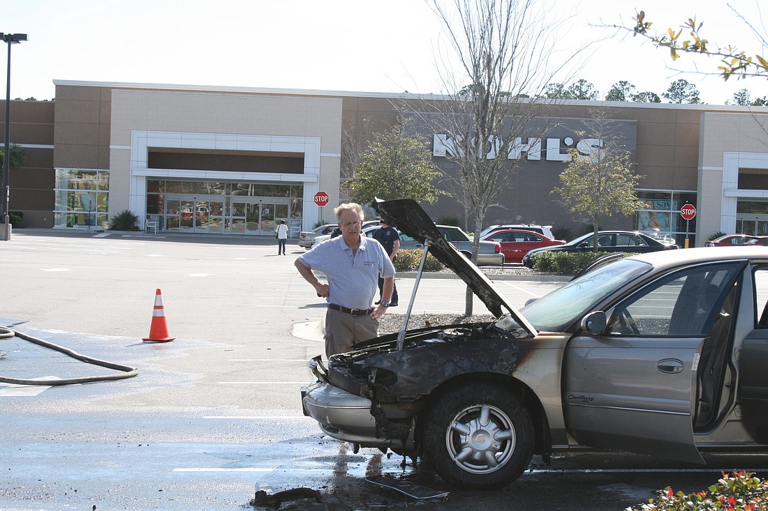 Merle Reid assesses the damage to his car after it caught fire Wednesday while he was shopping.