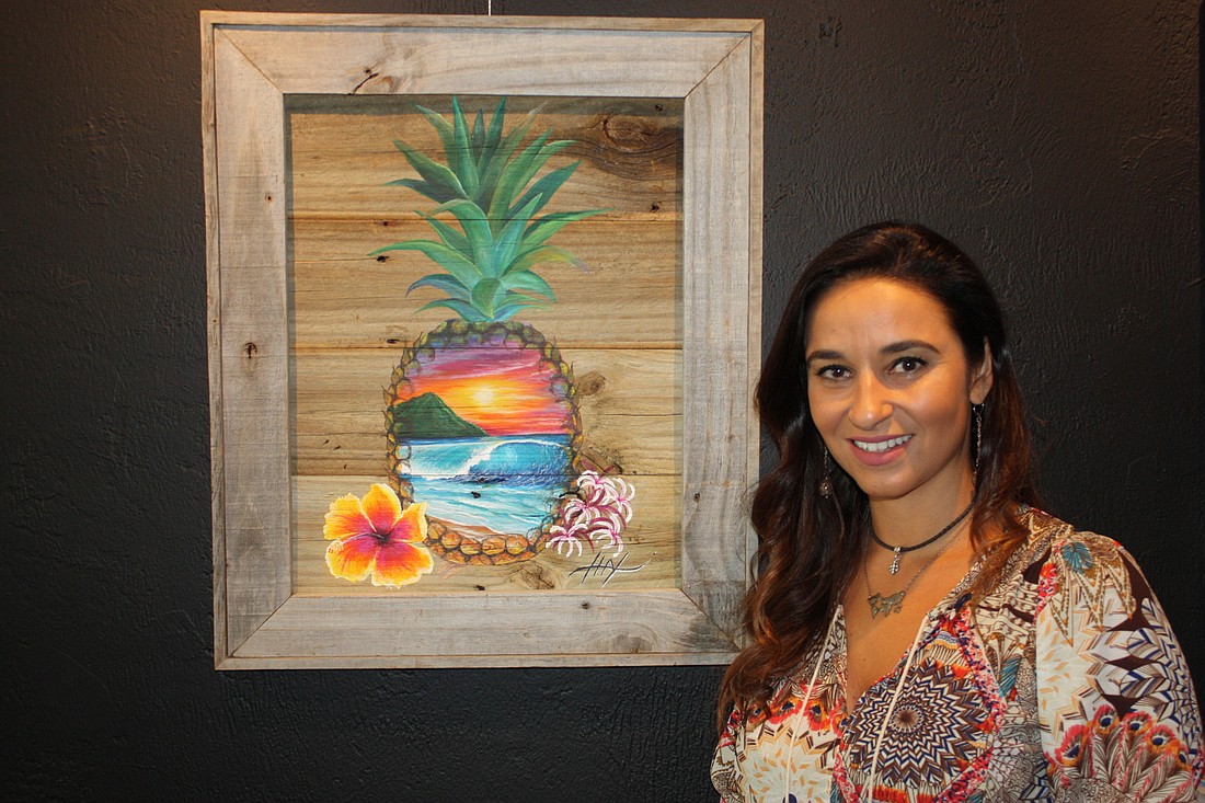 Thays Franca stands by art that was instrumental in her invitation to an art show in Hawaii for ocean-themed art. She paints on reclaimed wood from hurricane damage. Photo by Wayne Grant