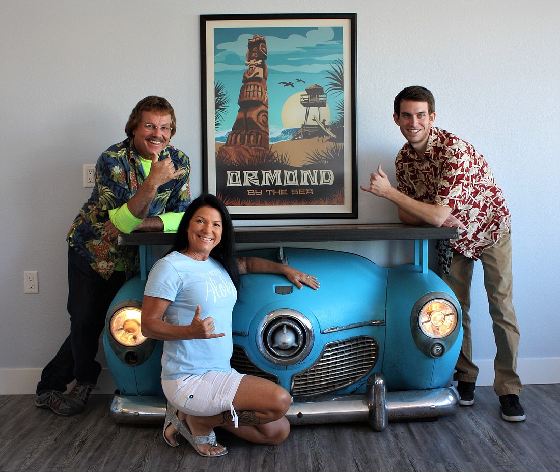 Angela DiMauro, real estate broker, has opened Aloha Realty with agents Dan Giaimo and Matt Oechslin. Not shown is Lorraine Hunnefeld. DiMauro purchased the car hood for the new office which has a surf motif. Photo by Wayne Grant