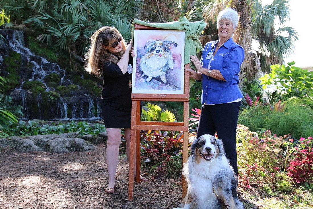 Pet Peace of Mind Coordinator Barbara Cady and Hospice Care volunteer Nancy Booher, along with Frankie, unveil his painting for Dogapalooza 2019. Photo by Jarleene Almenas