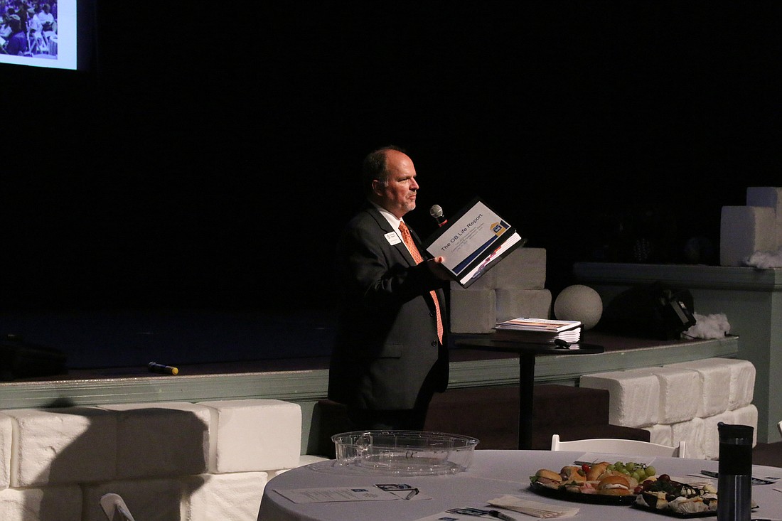 Ormond Beach Mayor Bill Partington holds up the 500-page OB Life report during the program summary on Tuesday, Jan. 22. Photo by Jarleene Almenas