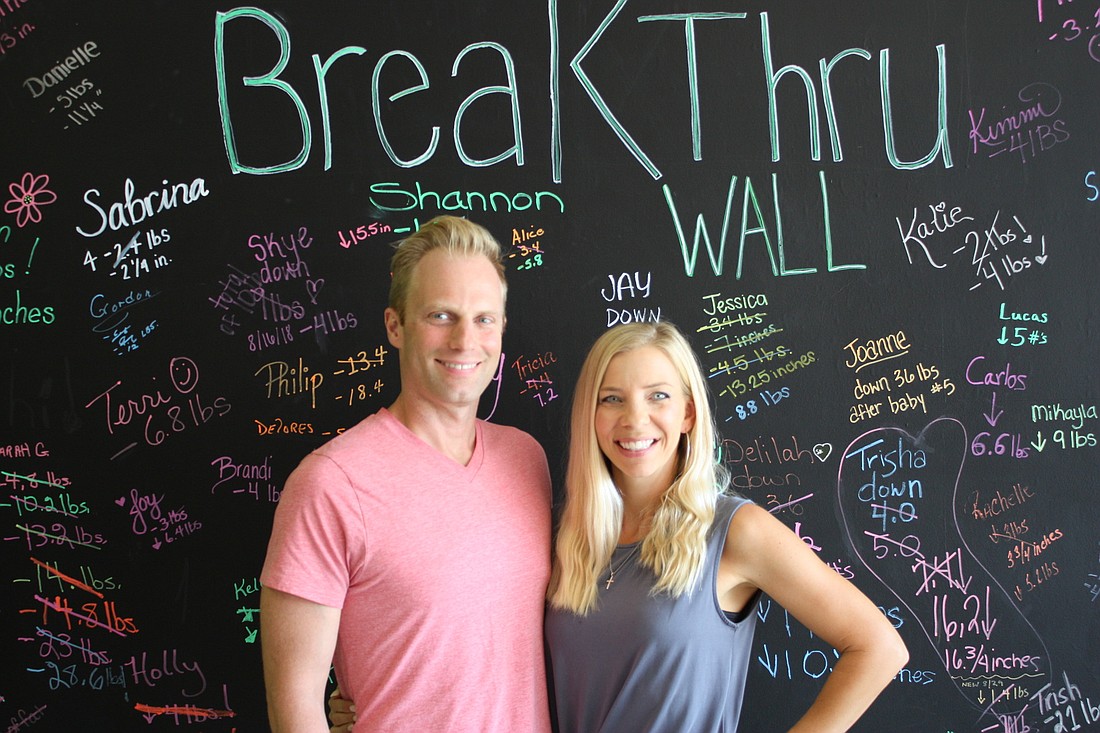 Lucas and Joanne Telfer stand in front of the BreakThru Wall at their new business. Photo by Wayne Grant