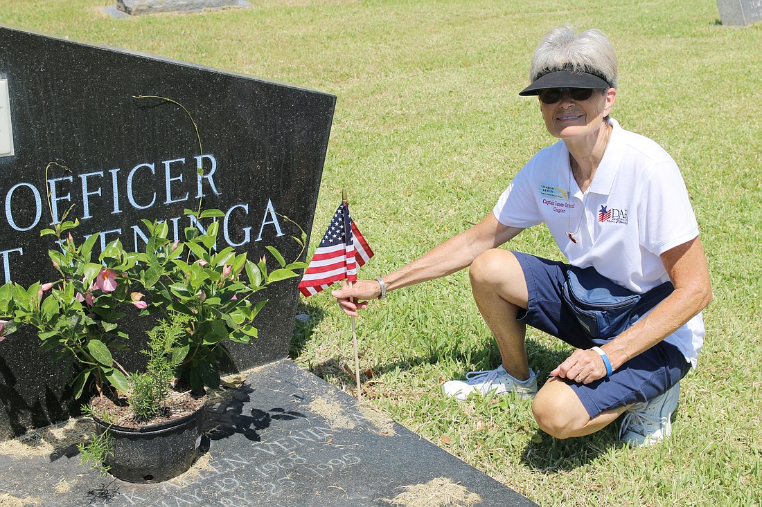 Sharon Lehto, of the Captain James Ormond chapter of the DAR, places a flag by a grave at Hillside Cemetery on Saturday, May 25. Photo by Jarleene Almenas