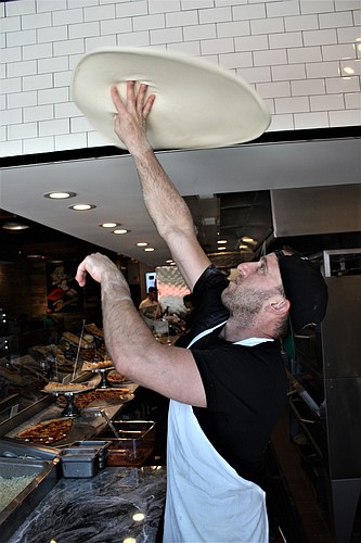 Alex Stephens prepares a pizza at Bronx House Pizza. Photo by Wayne Grant