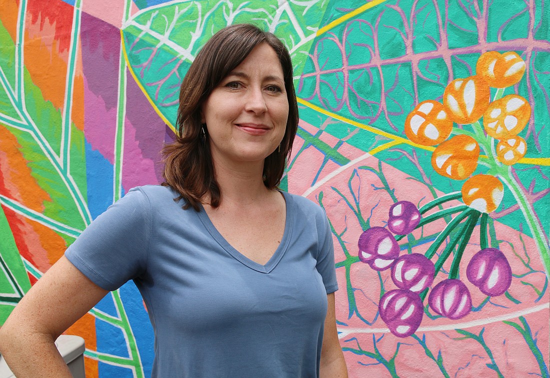 Beth O'Connor poses with her mural outside Frame of Mind. Photo by Jarleene Almenas