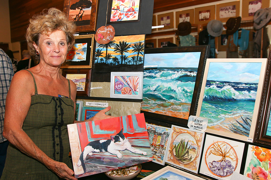 Ormond-by-the-Sea resident Christine Broussard poses with her paintings on sale at second-annual Hearts and Arts. File photo by Paige Wilson