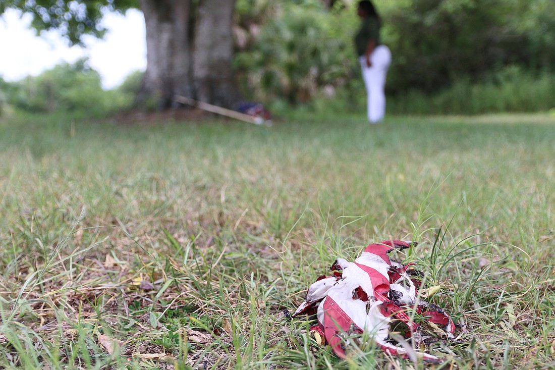 A flag lies tattered and burned on the grass at Oakridge Cemetery. Photo by Jarleene Almenas