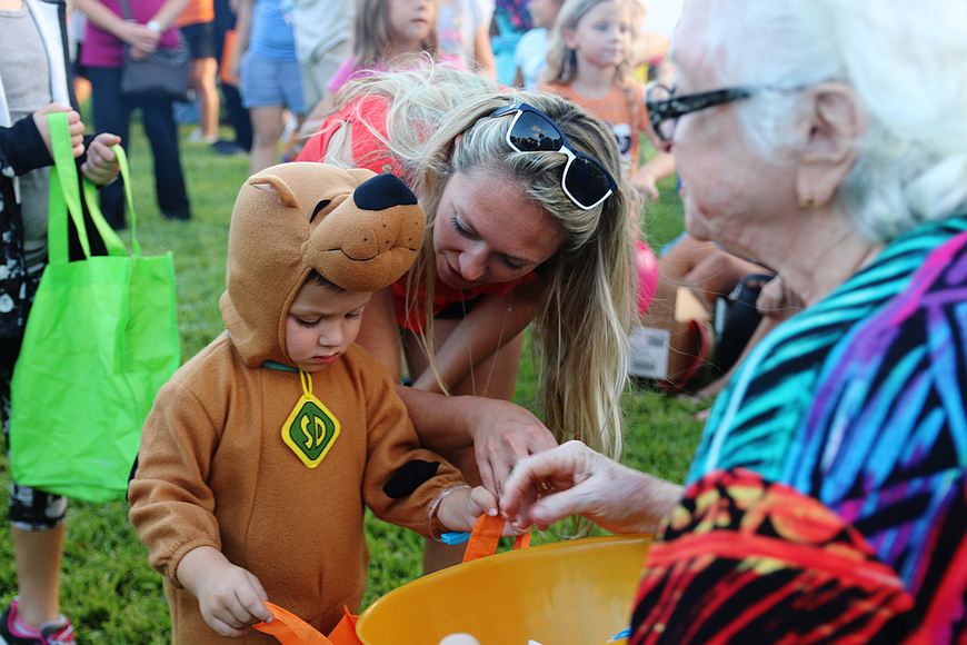 Mason Szumigala gets some candy from Realty Pros realtor Sue Kelley as his mom, Samantha Szumigala, encourages him at Realty Pros' Community Appreciation Night on Friday, Oct. 5, 2018. File photo by Jarleene Almenas