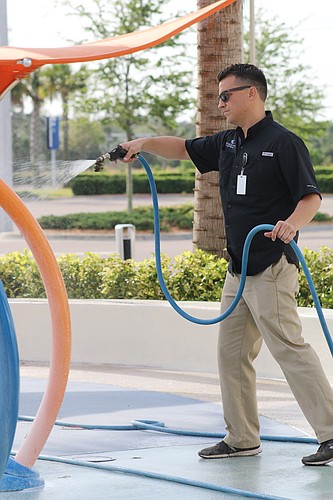 Chad Hatmaker cleans the splash pad at Tanger Outlets on Wednesday, March 18. Photo by Jarleene Almenas
