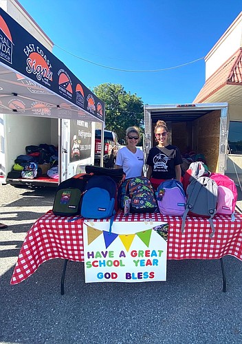 Cydney Reagan and Angelina Strickhouser were ready to distribute as many backpacks as they could during the giveaway on Saturday, Aug. 8. Courtesy photo