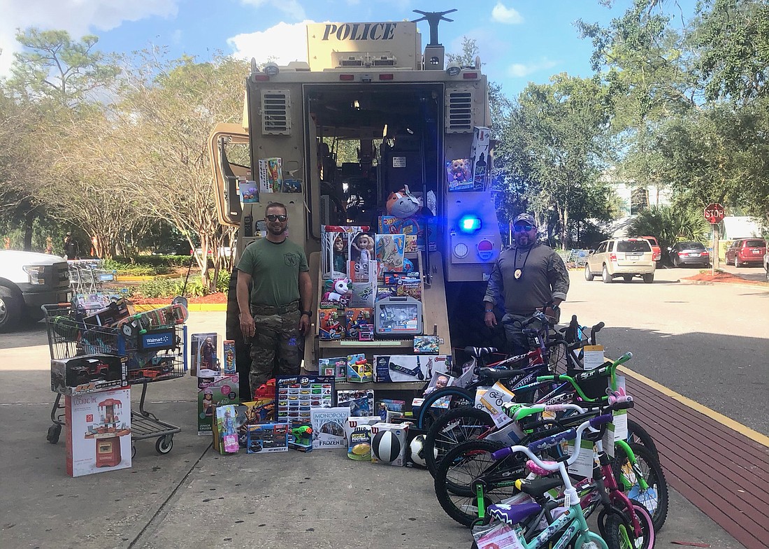 Ormond Beach Police Cpl. Caleb Braun and Capt. D.W. Smith stand in front of their department's MRAP during the first Grinch-busters toy drive. Courtesy photo