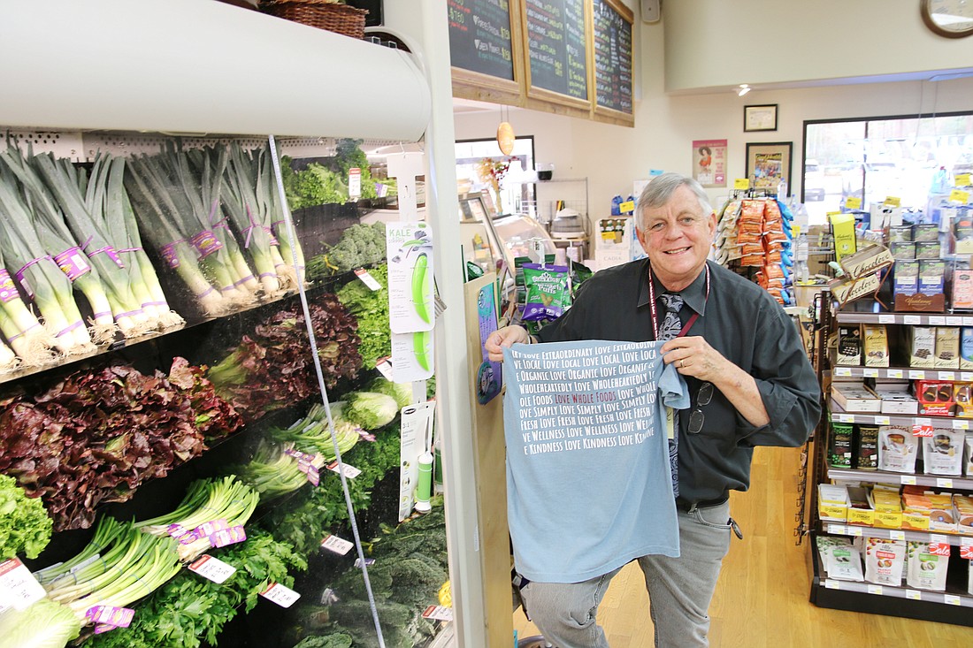 Love Whole Foods owner Mitch Booth holds up the back of one of his store's new T-shirts. Photo by Jarleene Almenas