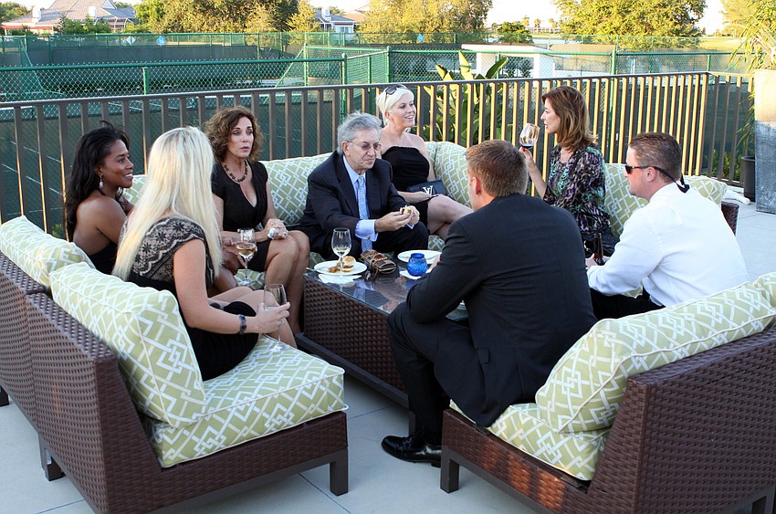 A group of Black Tie Bashers sit around talking at the Tennis Gardens