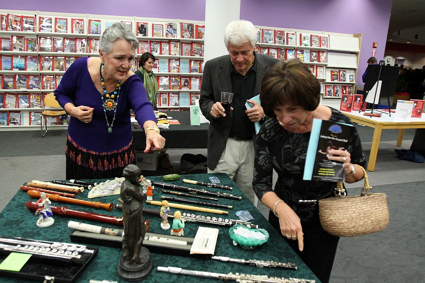Evelyn McFarland Miller shows Don and Linda Bruns her collection of flutes that she had on display Friday evening inside Selby Public Library.