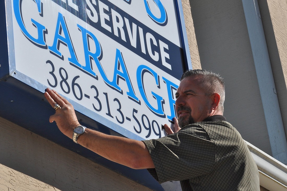 Del Hydrick hangs the sign for his new auto garage, at 2700 State Road 100. (Photo by Jonathan Simmons)