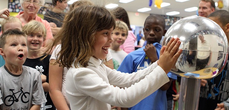 Avery Florio's hair sticks straight up after putting her hands on the Van De Graff generator at GWiz's table on Friday, Feb. 25 at Southside Elementary's Science Night.