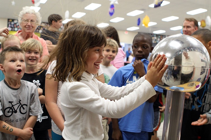 Avery Florio's hair sticks straight up after putting her hands on the Van De Graff generator at GWiz's table on Friday, Feb. 25 at Southside Elementary's Science Night.