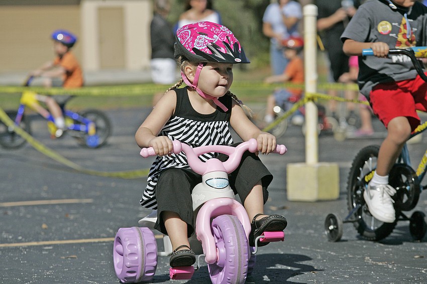 Four-year-old Chase Robeck made sure her helmet was securely fastened before mounting her tricycle.