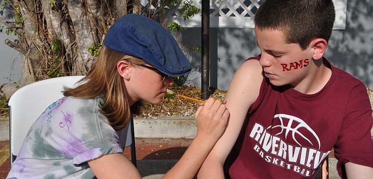 Riverview High School senior Amanda Rutherford paints an owl on A.J. Caldwell's arm.