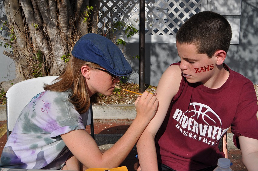 Riverview High School senior Amanda Rutherford paints an owl on A.J. Caldwell's arm.