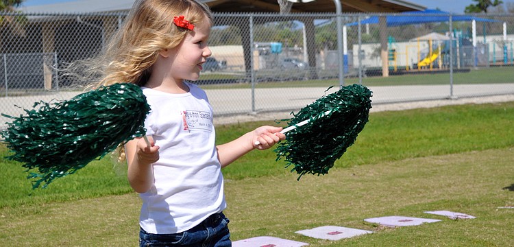 Cameron Seguin cheers on her big sister by waving pom-poms in the air.