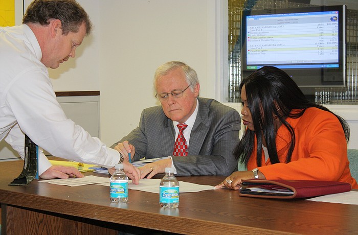 The canvassing board, City Attorney Robert Fournier, center, and City Auditor and Clerk Pamela Nadelini examine vote totals with an elections worker.