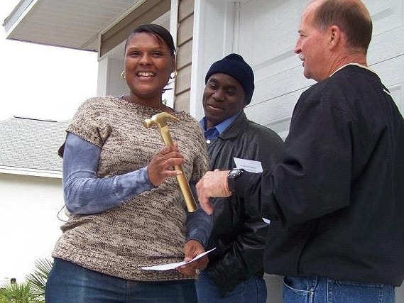 Janette and Stephen Knight receive a golden hammer as part of the home dedication.