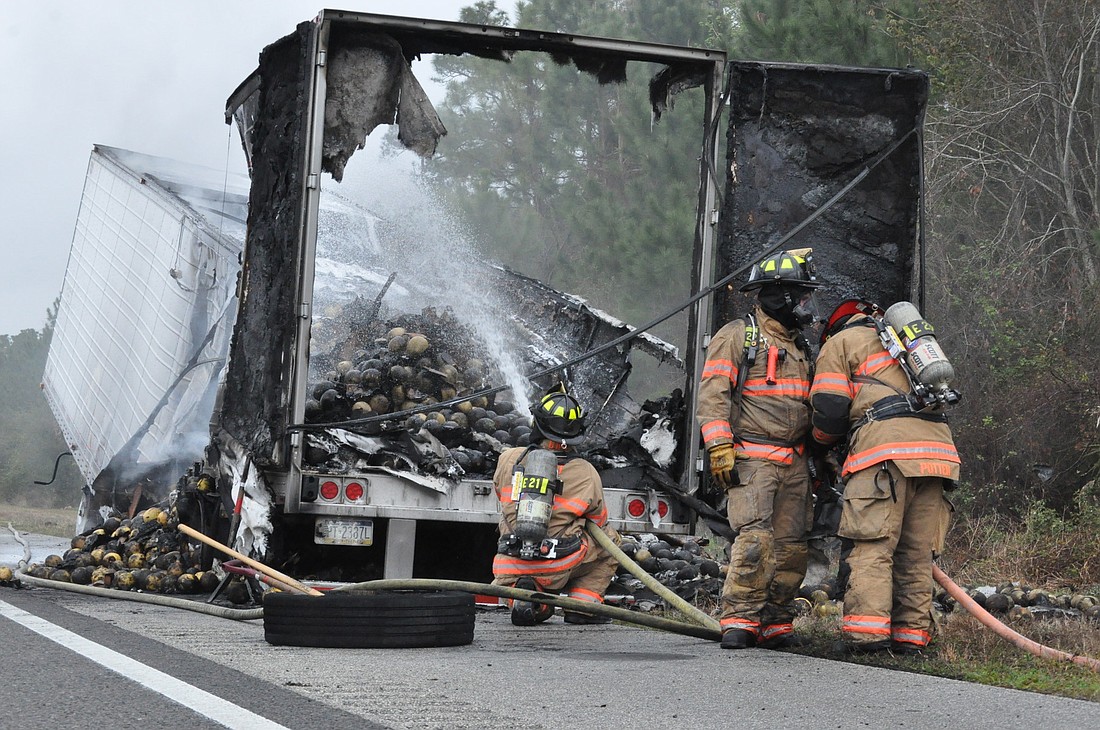 Crews from the Palm Coast Fire Department hose down the tractor-trailer about 45 minutes after it caught on fire on Tuesday. PHOTOS BY ANDREW O'BRIEN