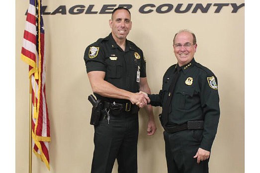 Flagler County Sheriff's Office Cmdr. Paul Bovino accepts his appointment from Sheriff Jim Manfre. COURTESY PHOTO