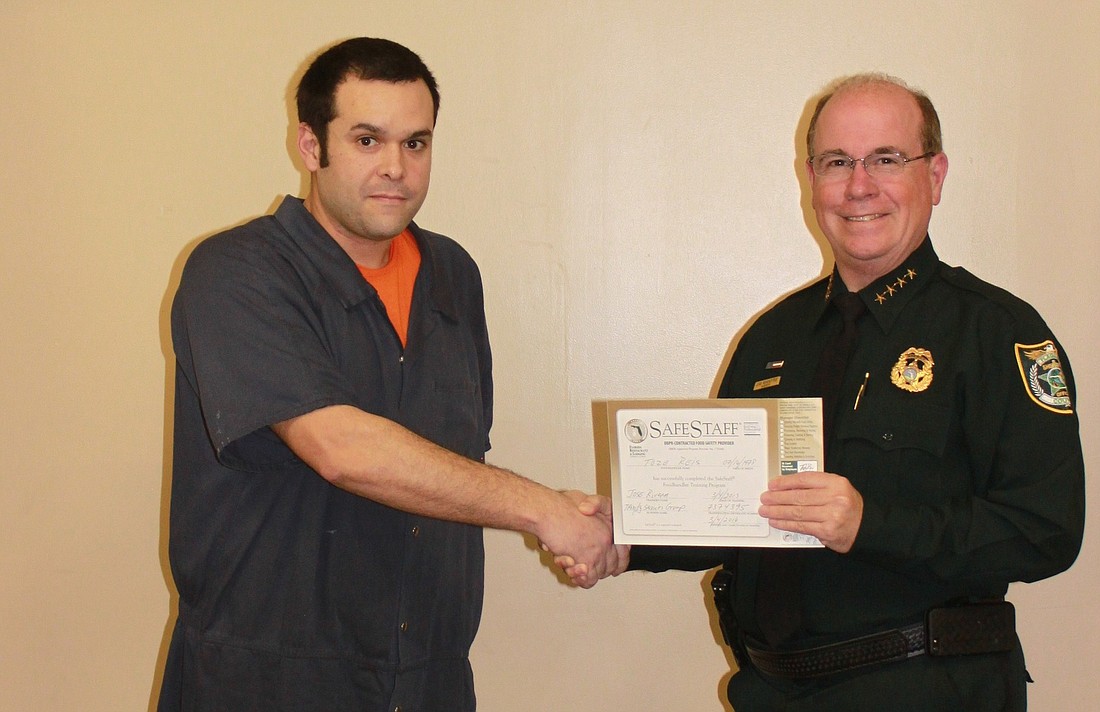 Toze Reis is presented his certificate by Flagler County Sheriff Jim Manfre.