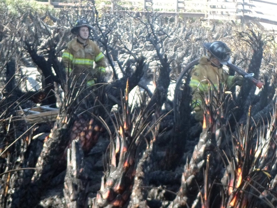 Firefighters work in the charred backyard of 3431 N. Oceanshore Blvd. Photo by Megan Hoye