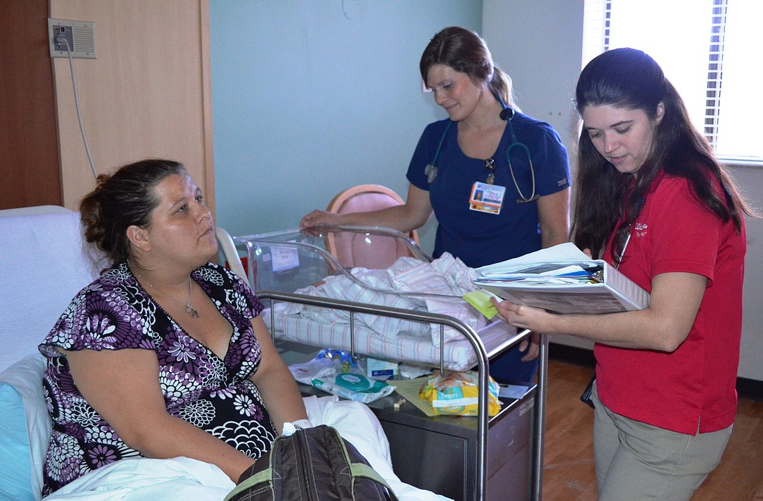 Rose Mineer, a pharmacy liaison, delivers prescriptions to Kimberli Dotts at her bedside as she prepares to go home after delivering a baby.