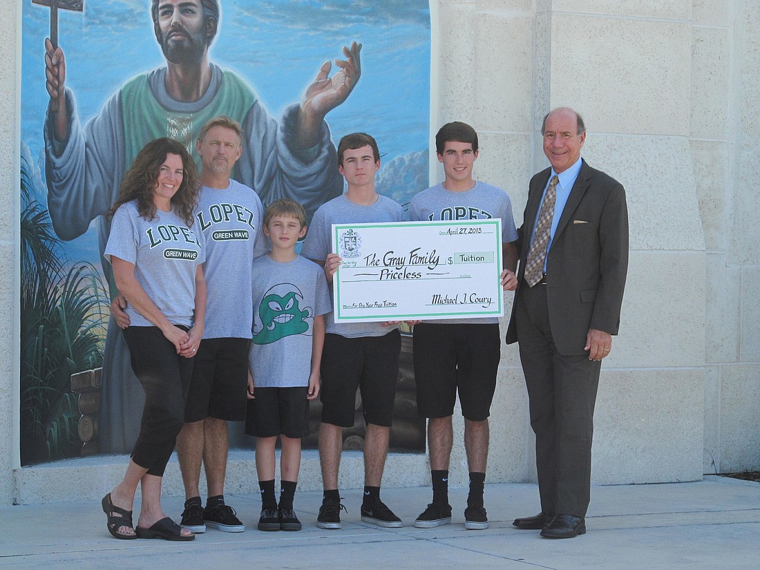 Father Lopez Catholic High School President Michael Coury presents free tuition to the Gray family, of Flagler Beach: Tammie, John, Lochlan, Mason and Charlie.