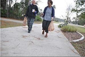 Nay Ouk and Cea Umak walk north on Belle Terre Parkway from the Town Center Shooping Plaza Friday morning. SHANNA FORTIER