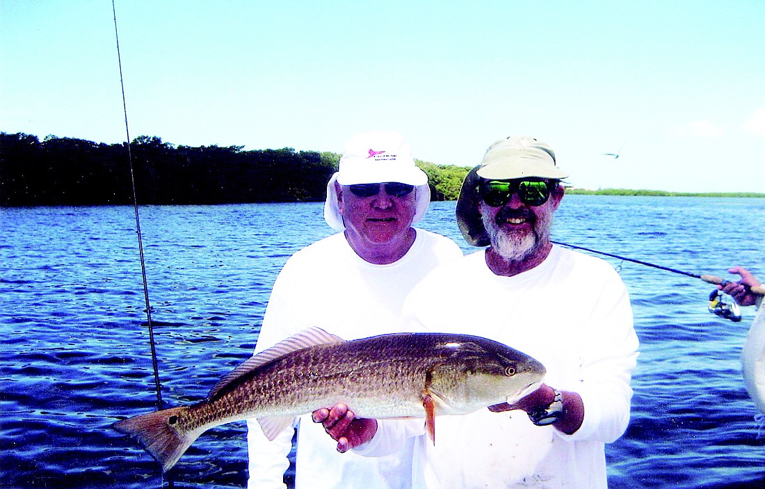 David Miller, with fishing guide Capt. Scott Moore, caught a red fish that he had to release.