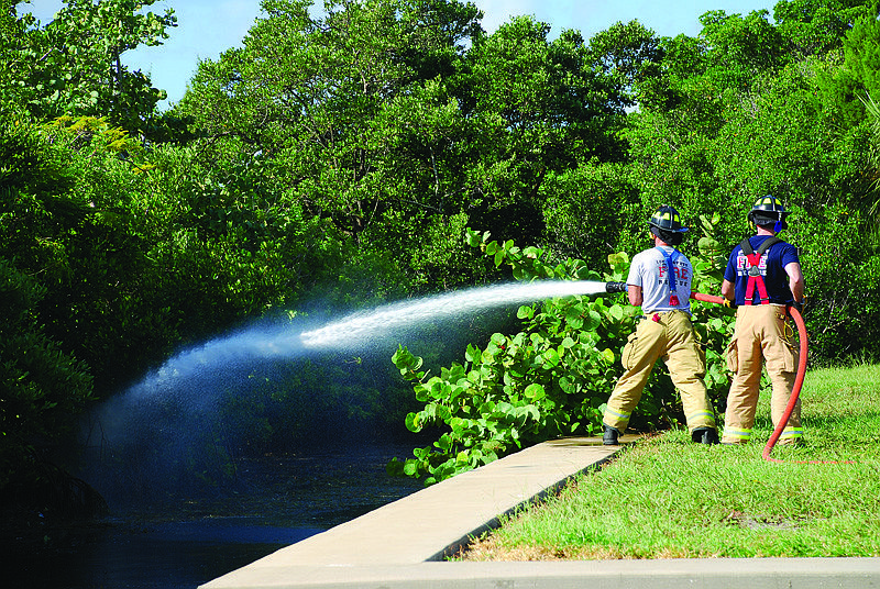 Firefighter/paramedics Alan Jenkins and Jason Coats flow a stream of water from a firehose into Sarasota Bay.