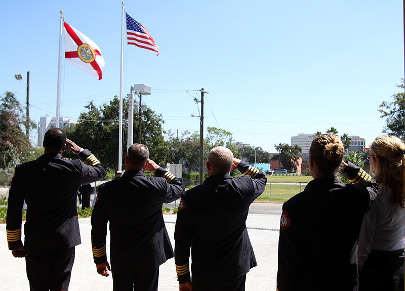 Fire Chief Kenneth B. Ellerbe, along with other members of the fire department, stand at attention for the raising of the flags and the Pledge of Allegiance during the ribbon-cutting ceremony held for Fire Rescue Station No. 1.