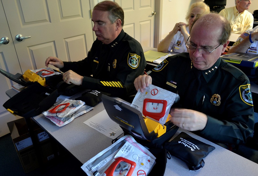 Flagler Coutny Sheriff James Manfre and Undersheriff Rick Staly open new AED units purchsed with city of Palm Coast traffic citation funds. (Courtesy photo.)