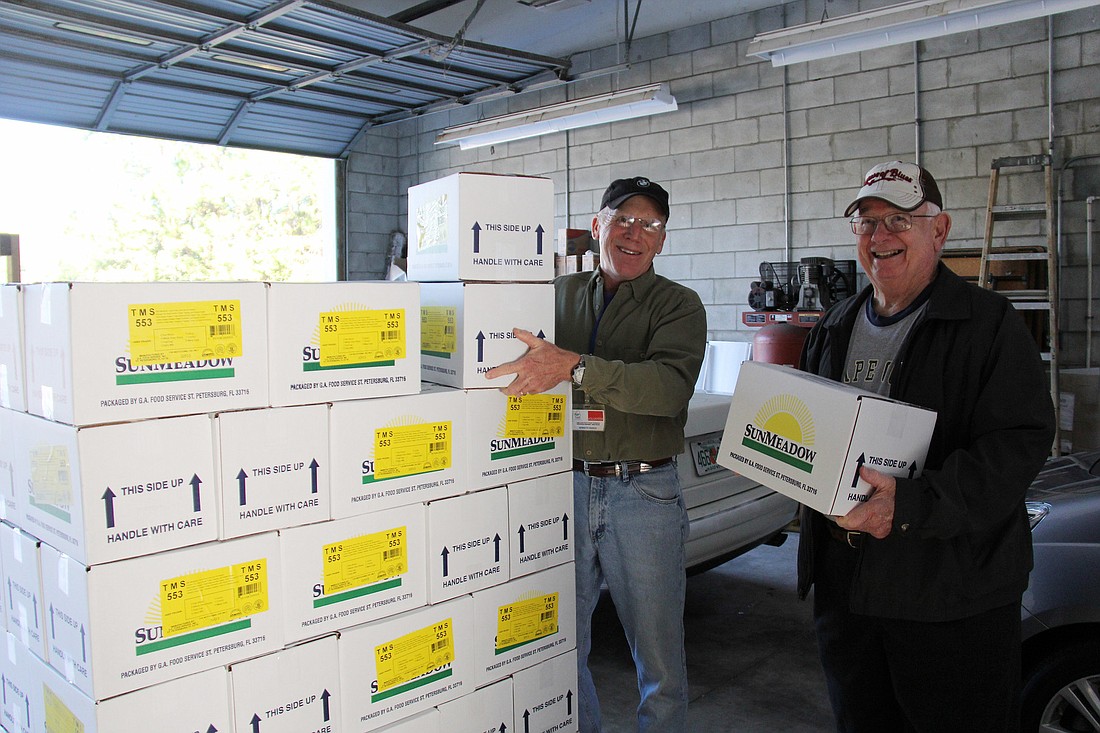 Volunteers Ken March and Allen Fletcher pack their cars for delivery of meals Tuesday morning. PHOTOS BY SHANNA FORTIER