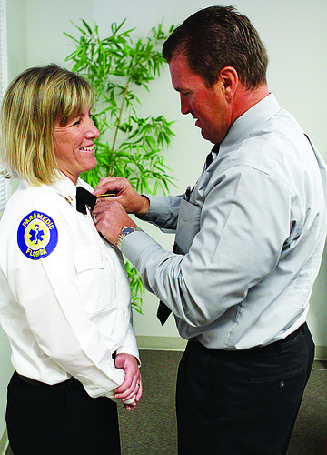 Billy Drake pins the deputy chief badge onto his wife's, Sandi, shirt.