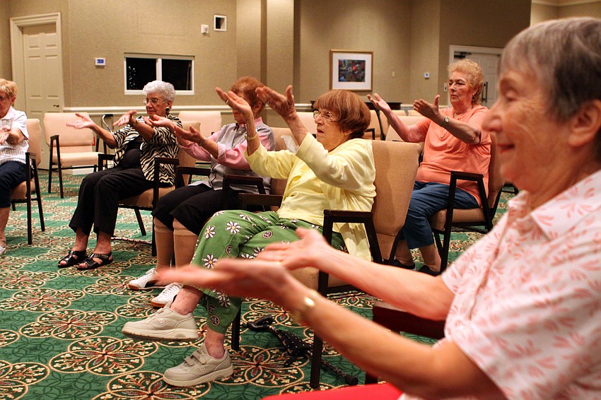 The chair dancers raise their hands up towards the ceiling.