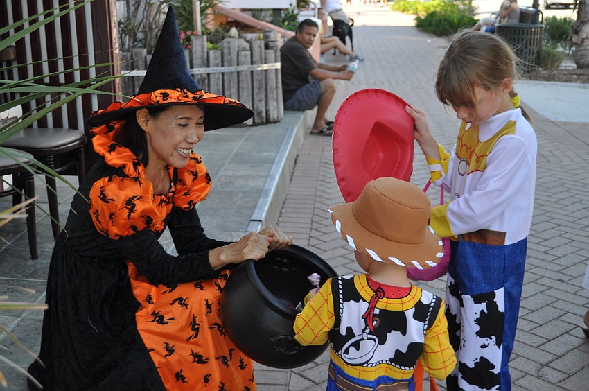 Ayako Tamaki of Joto Japanese Restaurant hands out candy to Allyson and Kyle Becker, dressed as Jessie and Woody from the Toy Story movies.