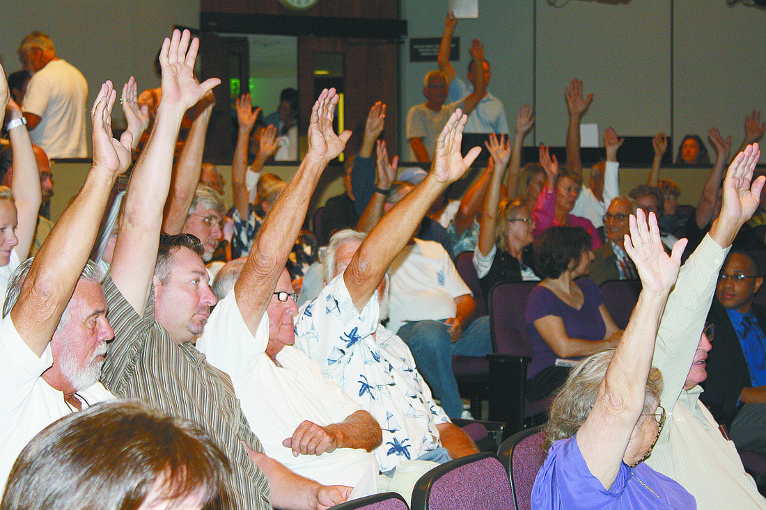 More than 100 Sailing Squadron supporters raise their hands Monday night to show their numbers in the commission chambers.