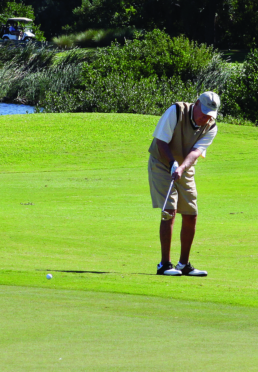 Paul Rudder hits his golf ball onto the green during a game of golf Monday afternoon at Longboat Key Club's golf course.