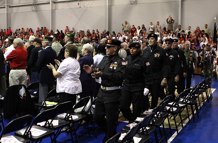 Veterans file into the gym and into the rows of seating set up for them.