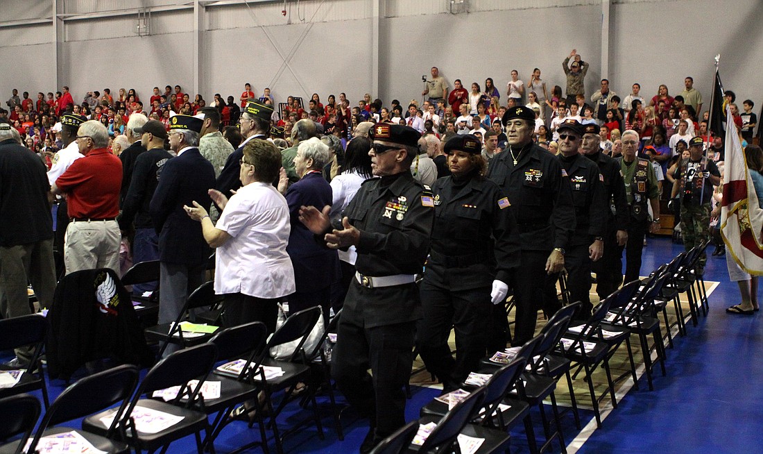 Veterans file into the gym and into the rows of seating set up for them.