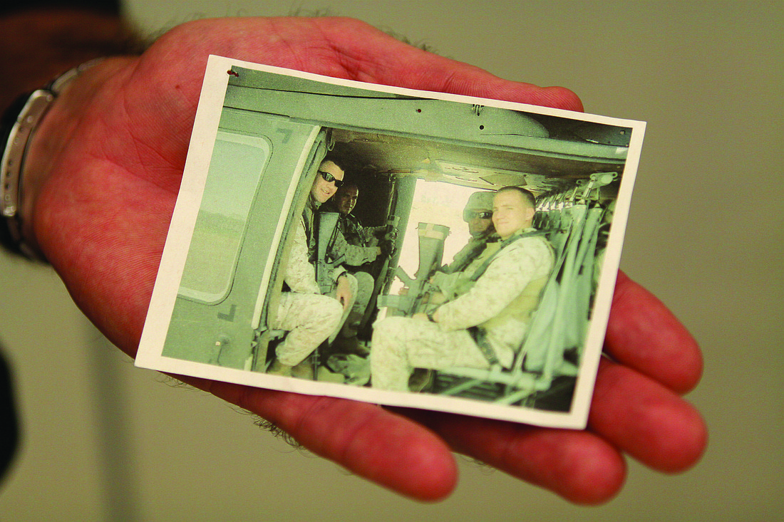 Maj. Jamie Purmort holds a photo of himself and three fellow Marines lifting off in a helicopter in June 2004 on his last day in Iraq.